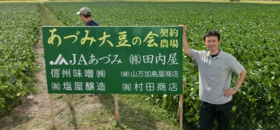 あづみ大豆の会の看板と大豆畑の写真