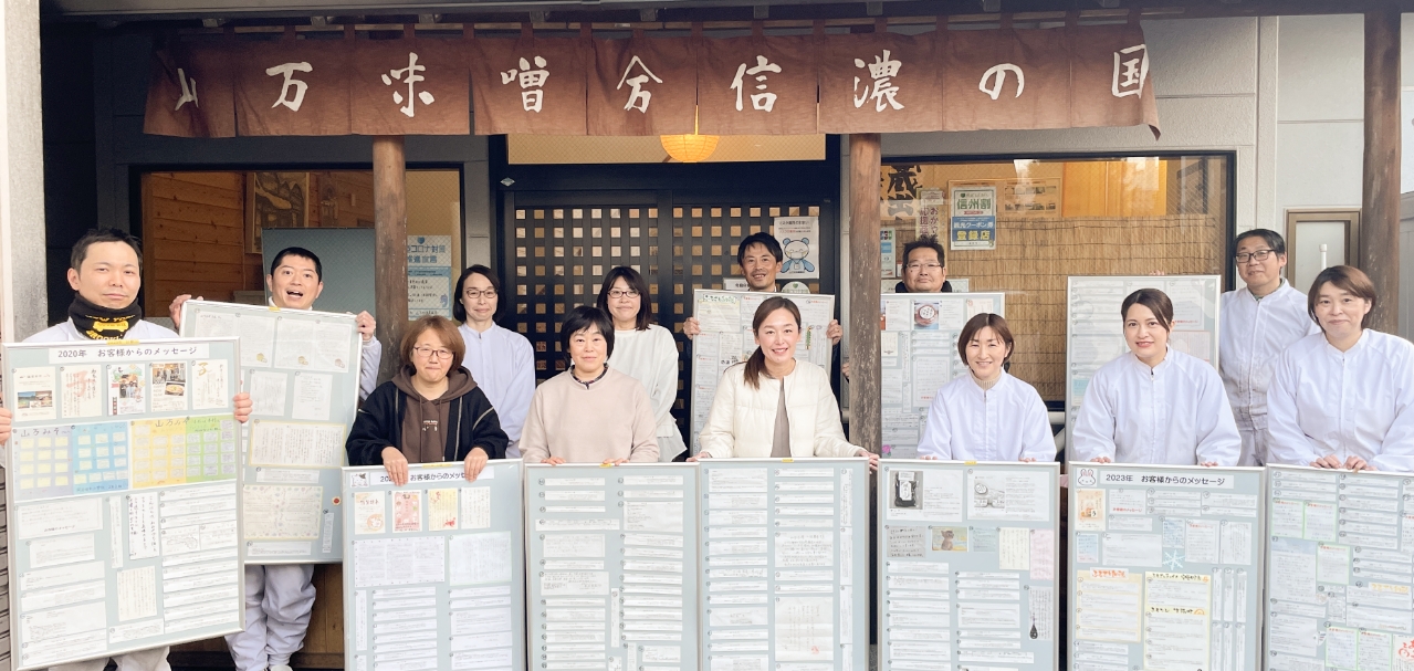 お客様の声に囲まれた山万味噌のスタッフの写真